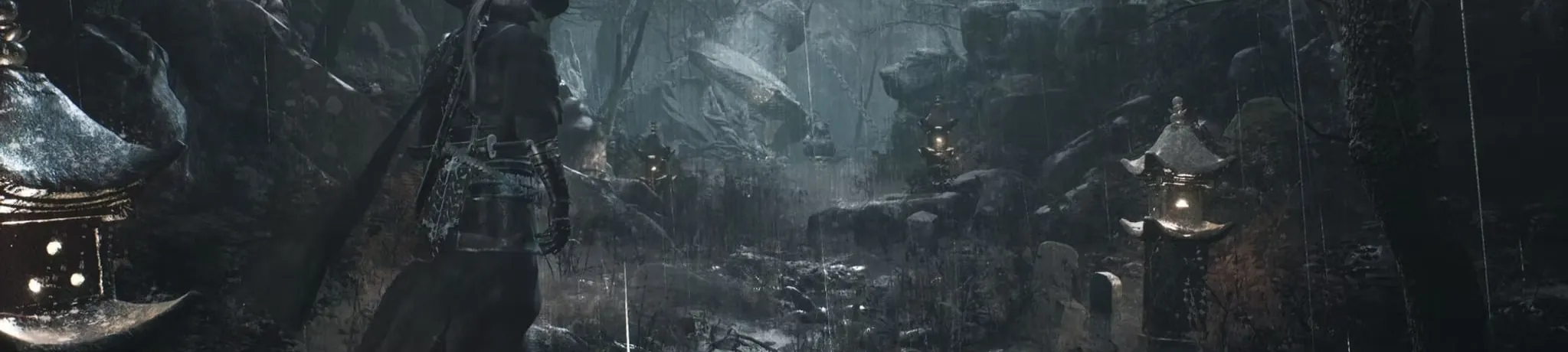 A figure in a straw hat on a rocky path in the rain, stone lanterns lit on either side.