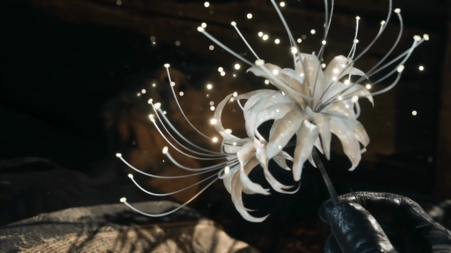 A gauntleted hand holds a white flower whose long stamens glow at the tips.