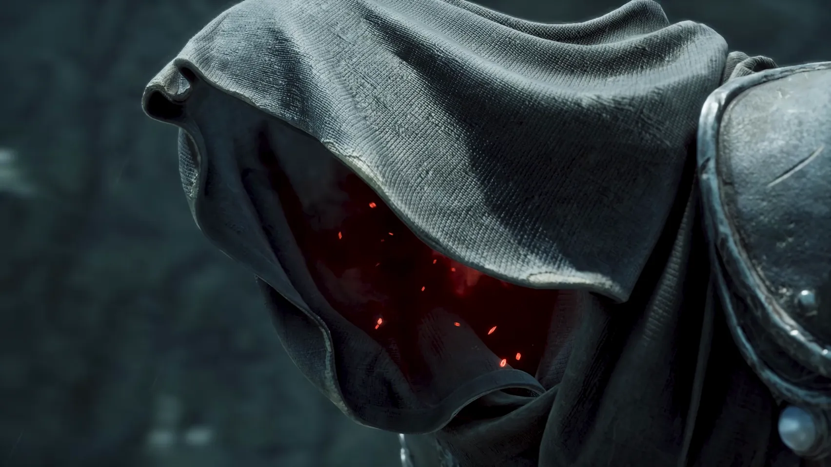 Close-up of a heavy grey hood with red points glowing in the shadow inside.