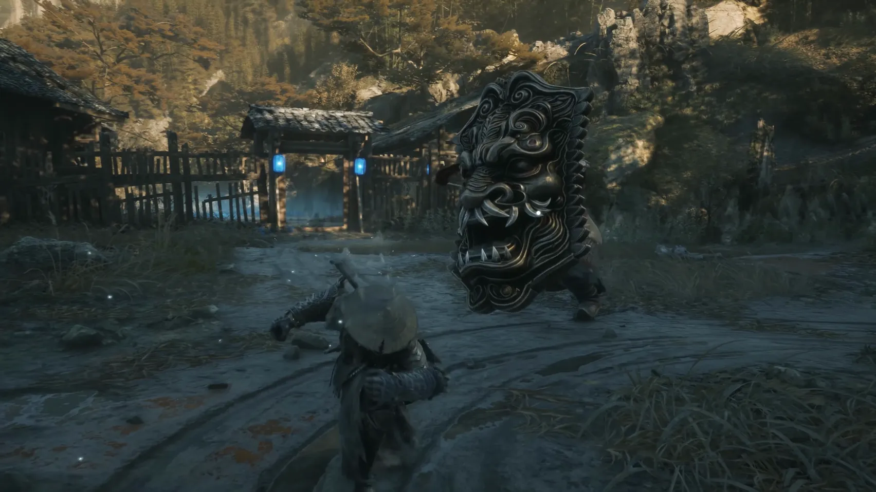A figure holding a huge carved shield stands in a village yard; a straw hat in the foreground.