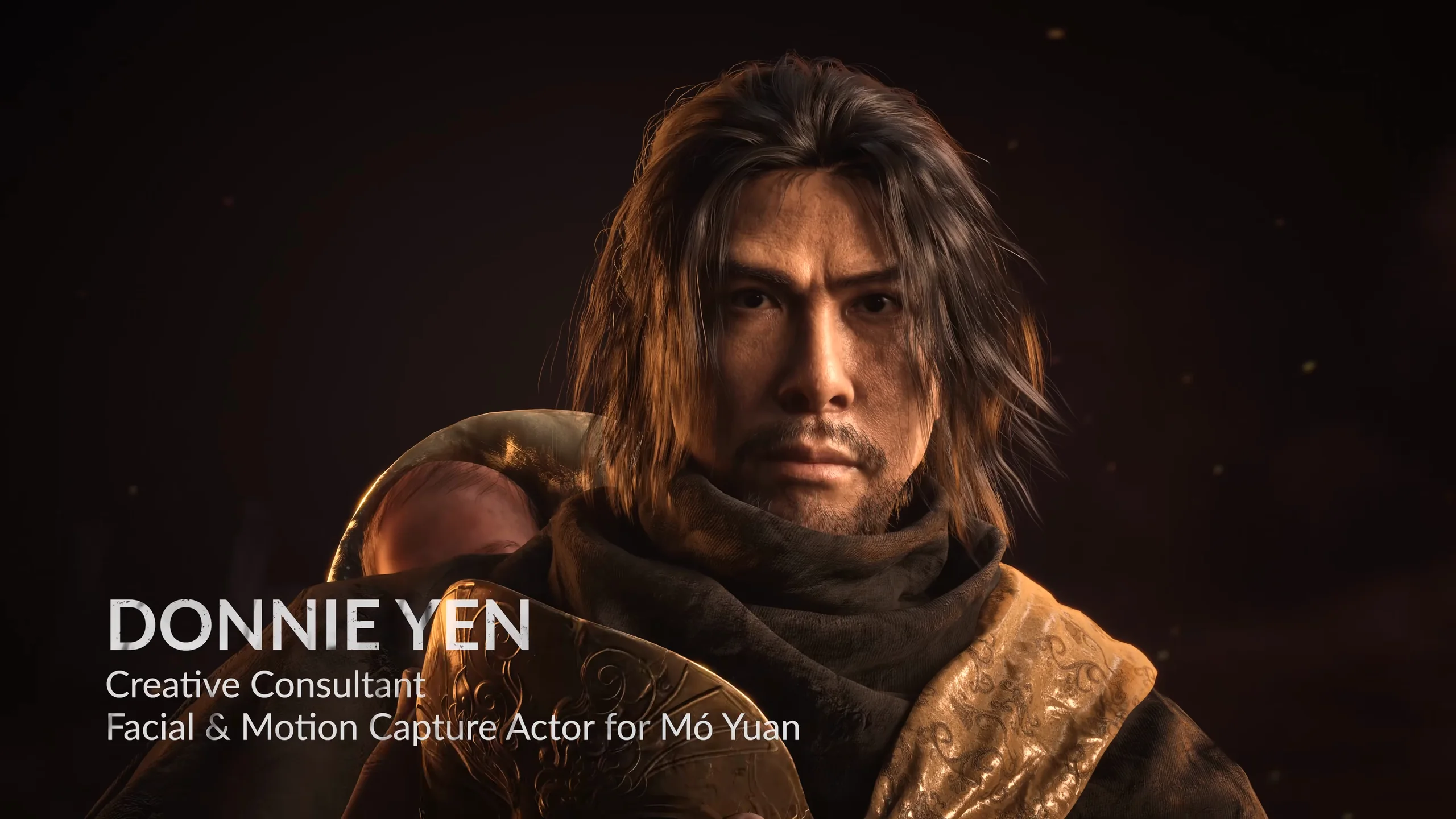 A long-haired man holds an infant; a title card at the lower left.