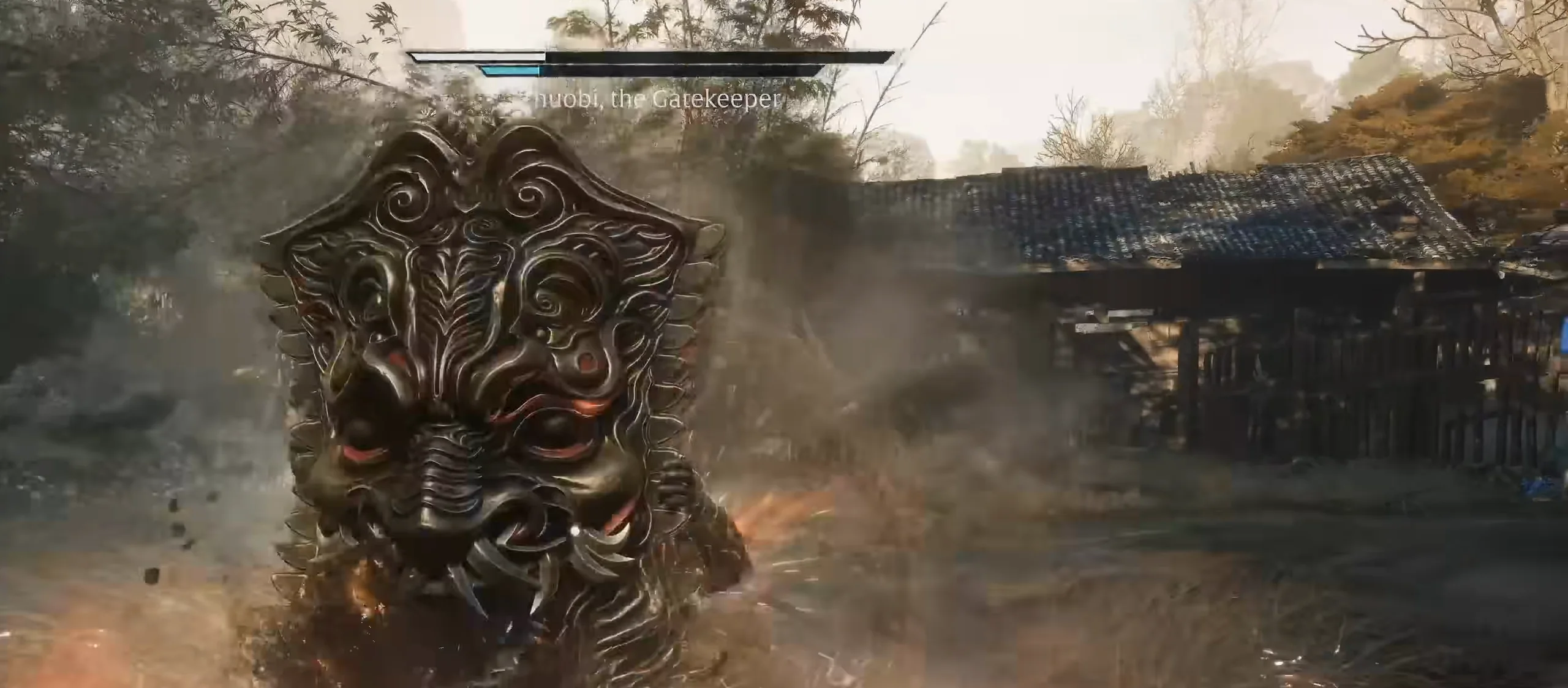 A huge shield carved with a beast’s face fills the left of the frame in a village yard; smoke and orange sparks around it.