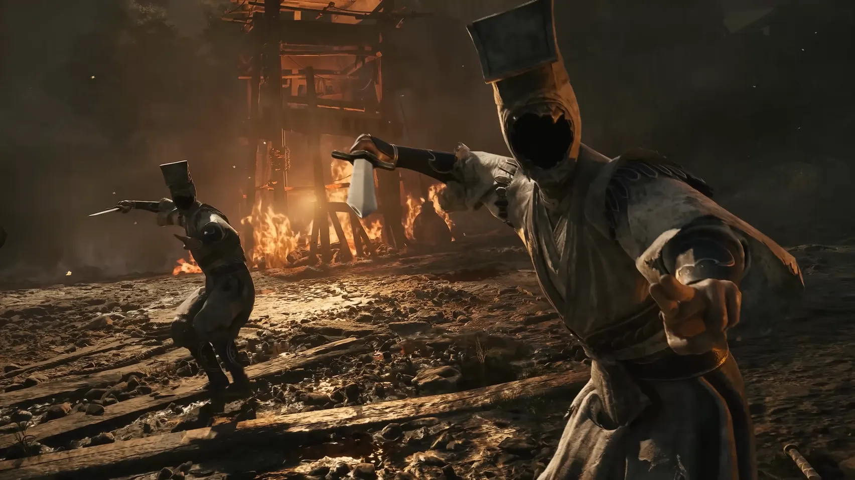 Close shot of two swordsmen in tall square hats with dark faces, before a burning tower.