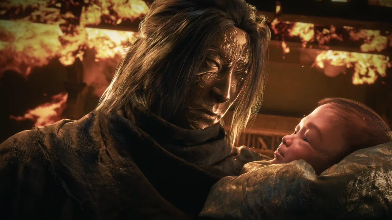 A long-haired man, one side of his face covered in engraved metal, holds a baby before a burning building.